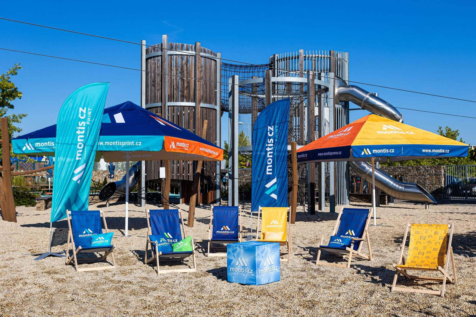 montis-cz-obrandovane-produkty-v-exterieru Realizace firemního brandingu na venkovním vybavení MONTIS CZ – reklamní slunečníky, lehátka a vlajky v praxi.